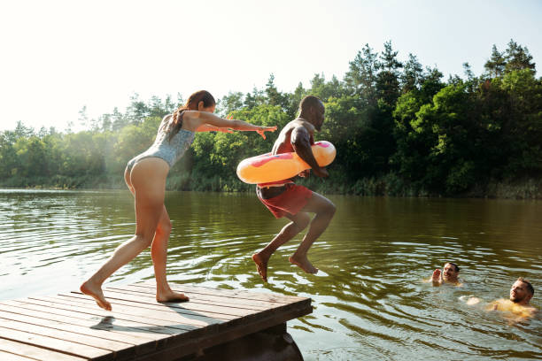 istock Happy friends having fun, jumping and swimming in river 1166361923