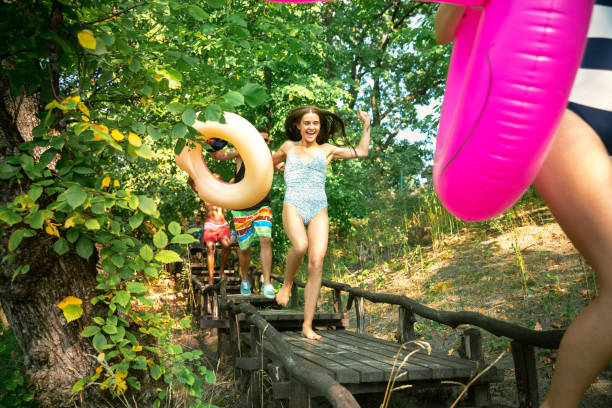 istock Group of happy friends having fun while running to swim on river 1166361927