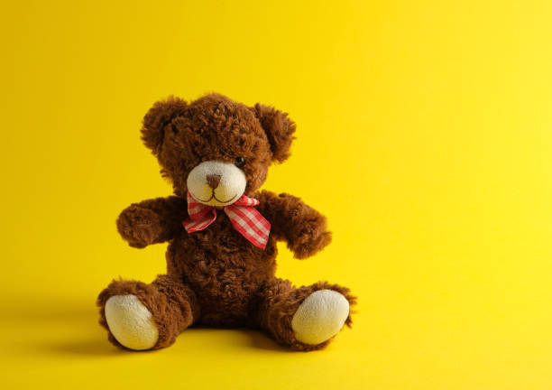 istock brown teddy bear sitting on a yellow background 1166362016