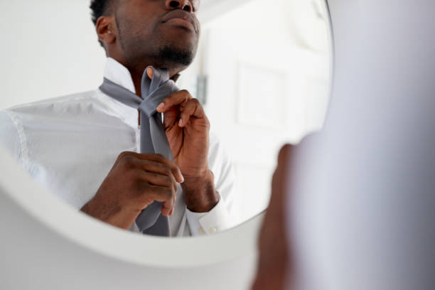 homme d'affaires à la maison attachant le necktie dans le miroir avant de partir pour le travail - tied up photos et images de collection