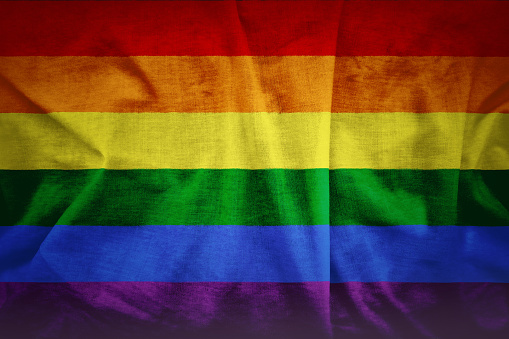 Fabric texture of gay rainbow flag background. A grunge background of the LGBT flag.