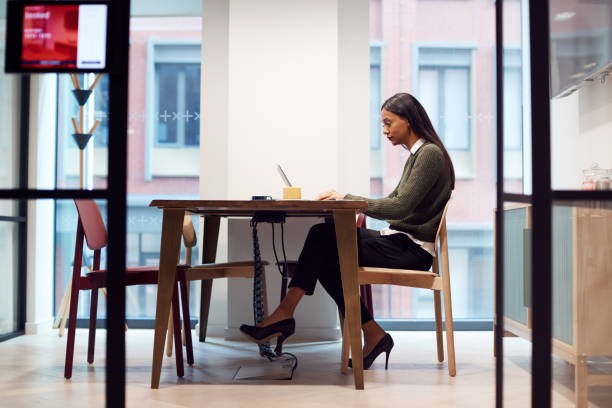 businesswoman working on laptop at desk in meeting room - hot desking imagens e fotografias de stock