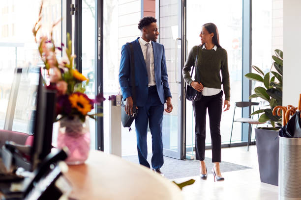 businessman and businesswoman arriving for work at office walking through door - returning imagens e fotografias de stock