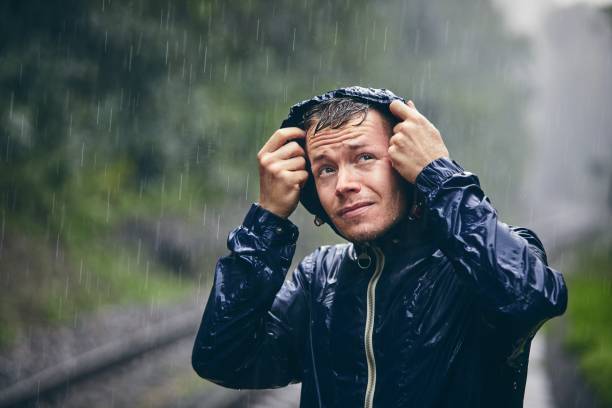 Traveler in heavy rain Trip in bad weather. Portrait of young man in drenched jacket in heavy rain. hood clothing stock pictures, royalty-free photos & images