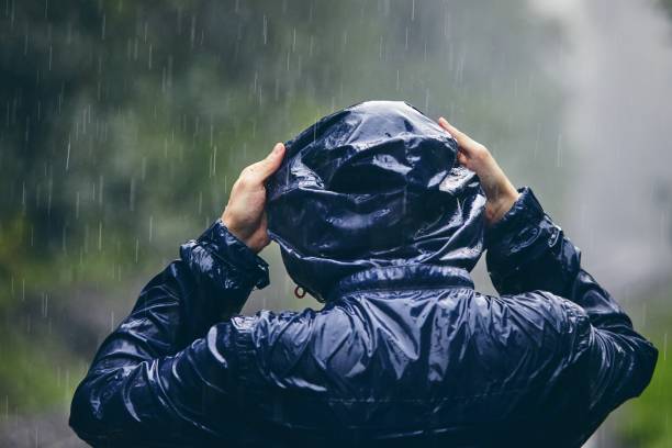 Traveler in heavy rain Trip in bad weather. Rear view of young man in drenched jacket in heavy rain. raincoat stock pictures, royalty-free photos & images