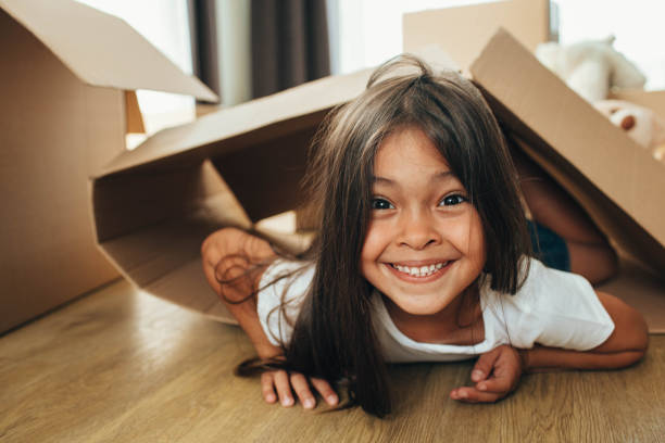 istock Happy mixed race little girl playing with cardboard boxes, having fun while moving home 1166364510