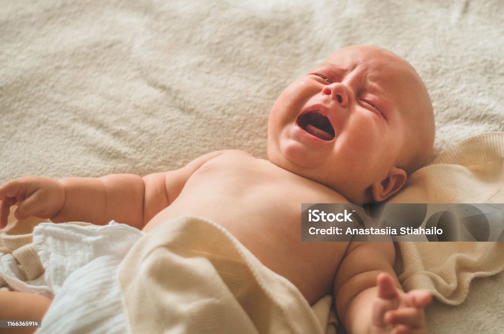 Crying hungry newborn baby lying on the bed. Love baby. Newborn baby and mother Crying hungry newborn baby lying on the bed. Love baby. Newborn baby and mother. Crying Stock Photo