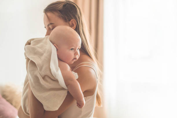 Home portrait of a newborn baby with mother on the bed. Mom holding and kissing her child Home portrait of a newborn baby with mother on the bed. Mom holding and kissing her child. Concept breast feeding cute boy show love symbol hand stock pictures, royalty-free photos & images