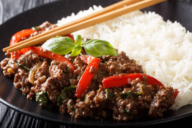 carne de res de albahaca tailandesa en salsa picante servida con arroz de cerca en un plato. horizontal - chopsticks stir fried vegetable beef fotografías e imágenes de stock