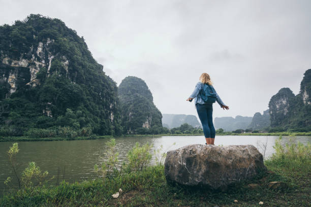 Caucasian blonde woman overlooking limestone mountains in Ninh Binh province, Vietnam stock photo