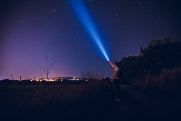 Man lighting up the stars Young caucasian man in the night, with a lantern in the hand doing a beam of light on a sky of stars. Stars exploring. lanterns at night stock pictures, royalty-free photos & images