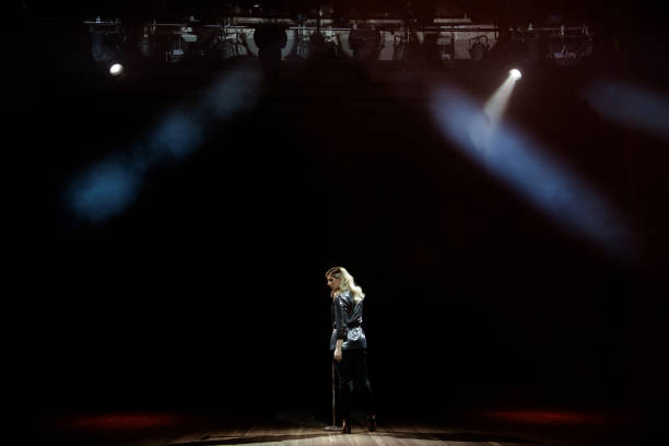 istock A young woman singer on stage during a concert view from the back. 1166371748