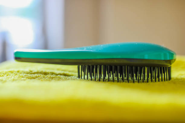 istock Green plastic hair brush on a yellow towel, side view with blurred background. 1166373409