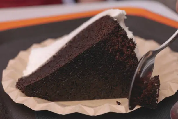 A single slice of guinness cake on a white platter. Naturally lit on a black surface.