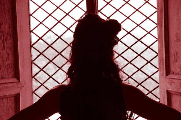 istock A girl looking outside through the window 1166374570