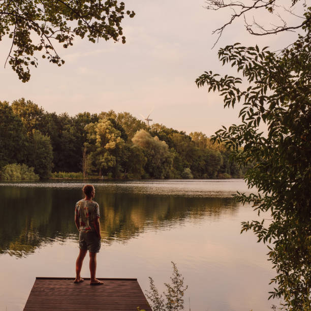 istock Man standing and looking at sunset by a lake 1166375158