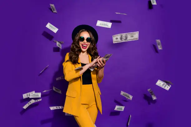 Portrait of her she nice attractive cheerful cheery positive trendy luxury, wavy-haired lady throwing 100 hundred million expenses isolated over bright vivid shine violet lilac background