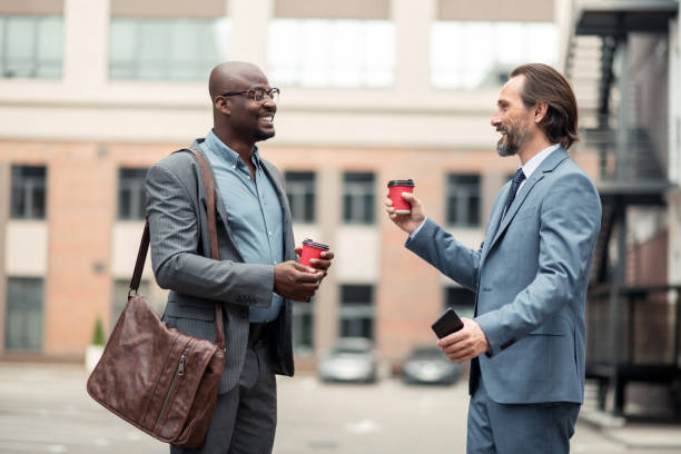 istock Bearded businessman speaking with colleague and drinking coffee 1166375326