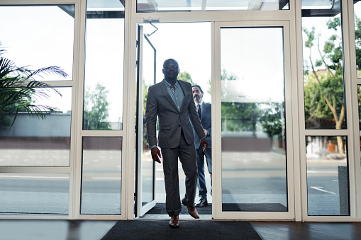 Entering business center. Two rich businessmen entering business center while having important meeting