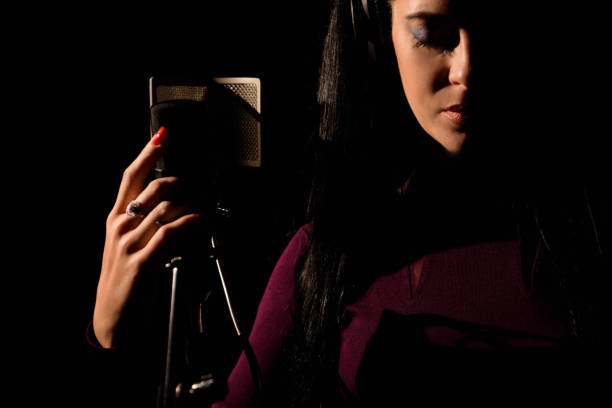 istock Female vocal artist singing in a recording studio. 1166376273