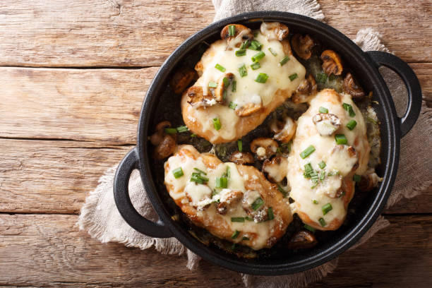 Lombardy Chicken breasts cooked with mushrooms, green onions, mozzarella cheese and parmesan closeup. horizontal top view Lombardy Chicken breasts cooked with mushrooms, green onions, mozzarella cheese and parmesan closeup in a pan on the table. Horizontal top view from above italian cheese stock pictures, royalty-free photos & images