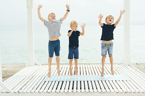 Three teenage boys on a summer day on the seashore having fun, jumping and joking.