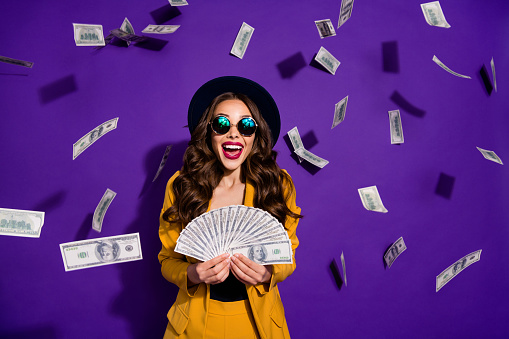 Portrait of her she nice lovely cheerful cheery luxury excited rich wealthy wavy-haired lady winner currency flying budget salary isolated over bright vivid shine violet lilac background