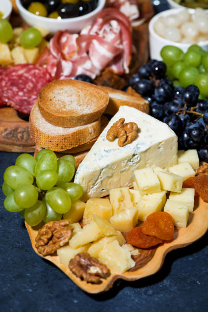 istock cheese platter on a wooden board, bread and fruit, vertical top view 1166376614