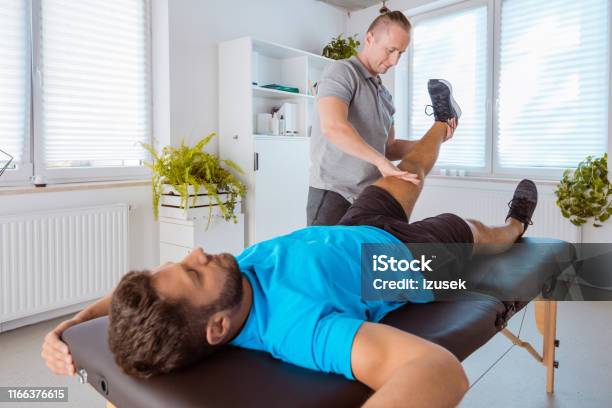 Therapist Massaging Young Man At Medical Center Stock Photo - Download Image Now - Adult, Adults Only, Alternative Therapy
