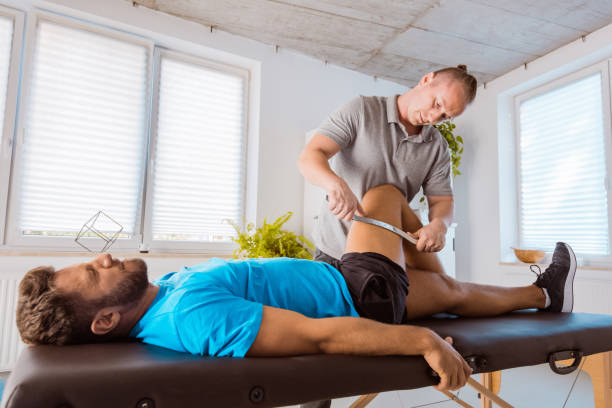 istock Therapist giving leg massage to young man 1166376879