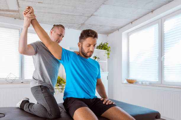 istock Therapist examining young man at rehab 1166378026