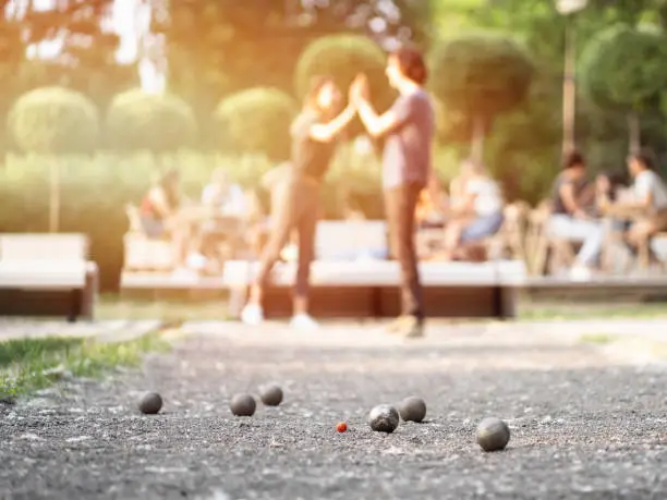Friends playing petanque in city park on a sunset