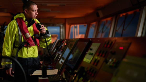 navegador. piloto, capitán como parte de la tripulación de la nave que realiza tareas diarias con radio vhf, prismáticos a bordo de la nave moderna con equipos de navegación de alta calidad en el puente al amanecer. - marine safety equipment audio fotografías e imágenes de stock