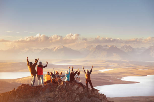 Large group of happy friends in mountains area Large group of happy friends is having fun on mountain top and looks at mountain's valley. Adventure or travel concept on top of stock pictures, royalty-free photos & images