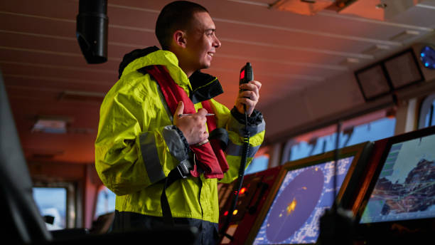 navigatore. pilota, capitano come parte dell'equipaggio della nave che svolge compiti quotidiani con radio vhf, binocolo a bordo di nave moderna con attrezzature di navigazione di alta qualità sul ponte all'alba. - sea safety antenna radar foto e immagini stock