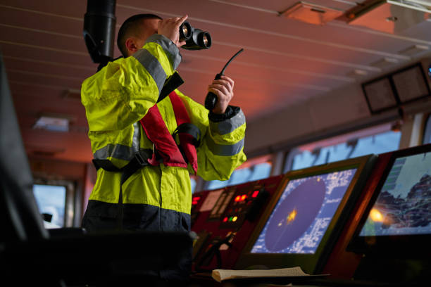 navigatore. pilota, capitano come parte dell'equipaggio della nave che svolge compiti quotidiani con radio vhf, binocolo a bordo di nave moderna con attrezzature di navigazione di alta qualità sul ponte all'alba. - sea safety antenna radar foto e immagini stock