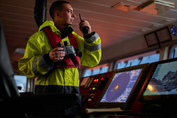 navegador. piloto, capitán como parte de la tripulación de la nave que realiza tareas diarias con radio vhf, prismáticos a bordo de la nave moderna con equipos de navegación de alta calidad en el puente al amanecer. - marine safety equipment audio fotografías e imágenes de stock