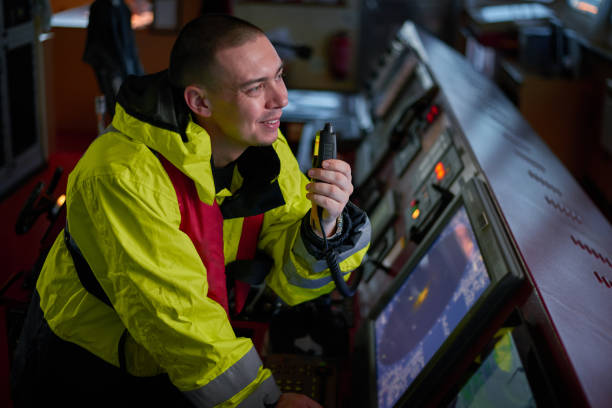 navigatore. pilota, capitano come parte dell'equipaggio della nave che svolge compiti quotidiani con radio vhf, binocolo a bordo di nave moderna con attrezzature di navigazione di alta qualità sul ponte all'alba. - sea safety antenna radar foto e immagini stock