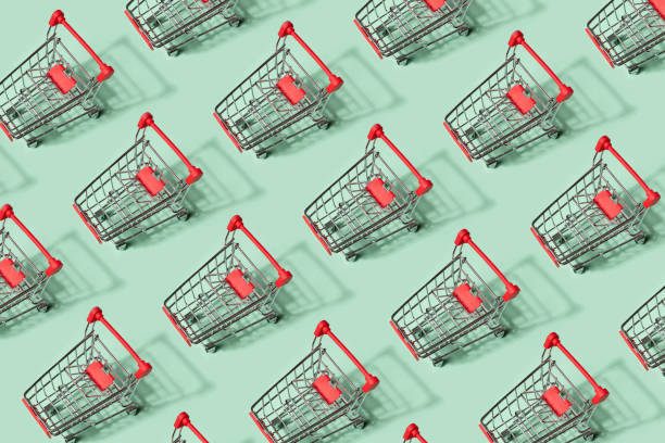 istock Small empty shopping carts perform a pattern on a pastel colored paper background. Modern trendy design for any purposes. 1166379884