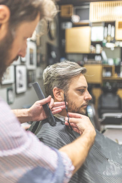 istock Barber cutting and modeling hair with scissors and comb. 1166379973