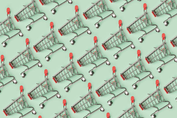 istock Small empty shopping carts perform a pattern on a pastel colored paper background. Modern trendy design for any purposes. 1166380250