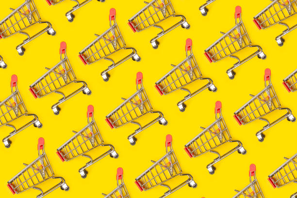 istock Small empty shopping carts perform a pattern on a pastel colored paper background. Modern trendy design for any purposes. 1166380529
