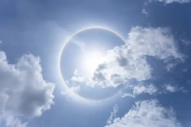 Sun with circular rainbow in day time or Sun halo on blue sky background with cloud