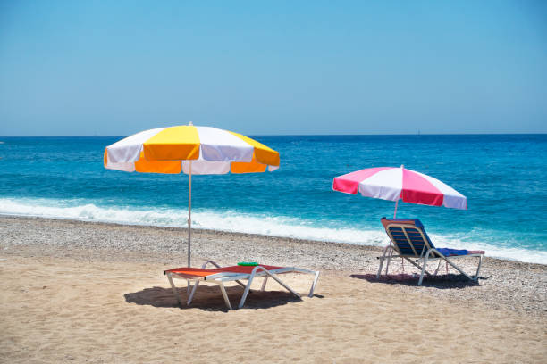 istock Multi colored umbrella and deck with towel on sand beach. 1166380672