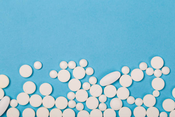 thème de pharmacie. différentes pilules et capsules blanches sur la surface bleue. closeup - hydrocodone photos et images de collection