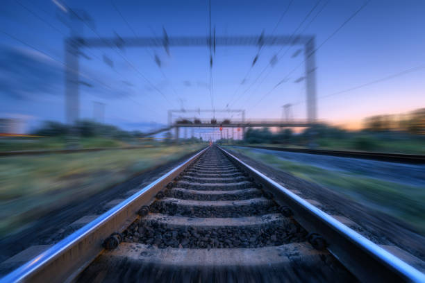 istock Railroad and blue sunset sky with clouds with motion blur effect. Industrial landscape with railway station and blurred background at twilight. Railway platform in move. Transportation. Speed motion 1166383678