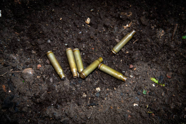 escudos vazios da espingarda da munição automática das armas dispersadas na terra - mass murder - fotografias e filmes do acervo