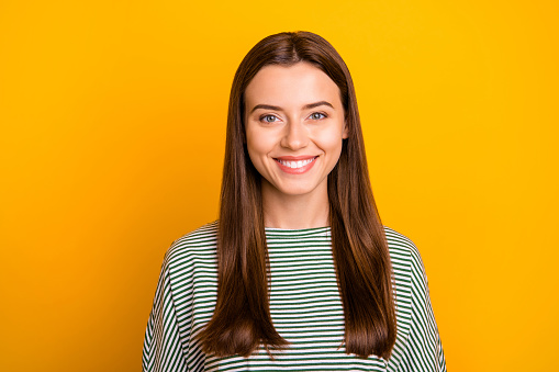 Photo of girl standing in front of camera, and trying not to blink while isolated with yellow background