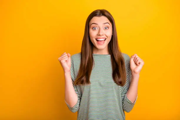 Photo of Photo of smiling shouting cheerful positive girlfriend having found dress she has wanted to obtain got cheaper by half while isolated with yellow background