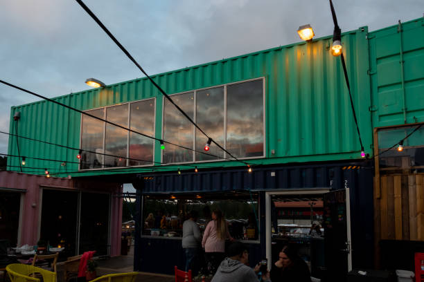 Outdoor front facade night view of  a container pop-up restaurant with windows and a bar with people in Ullared Sweden. stock photo